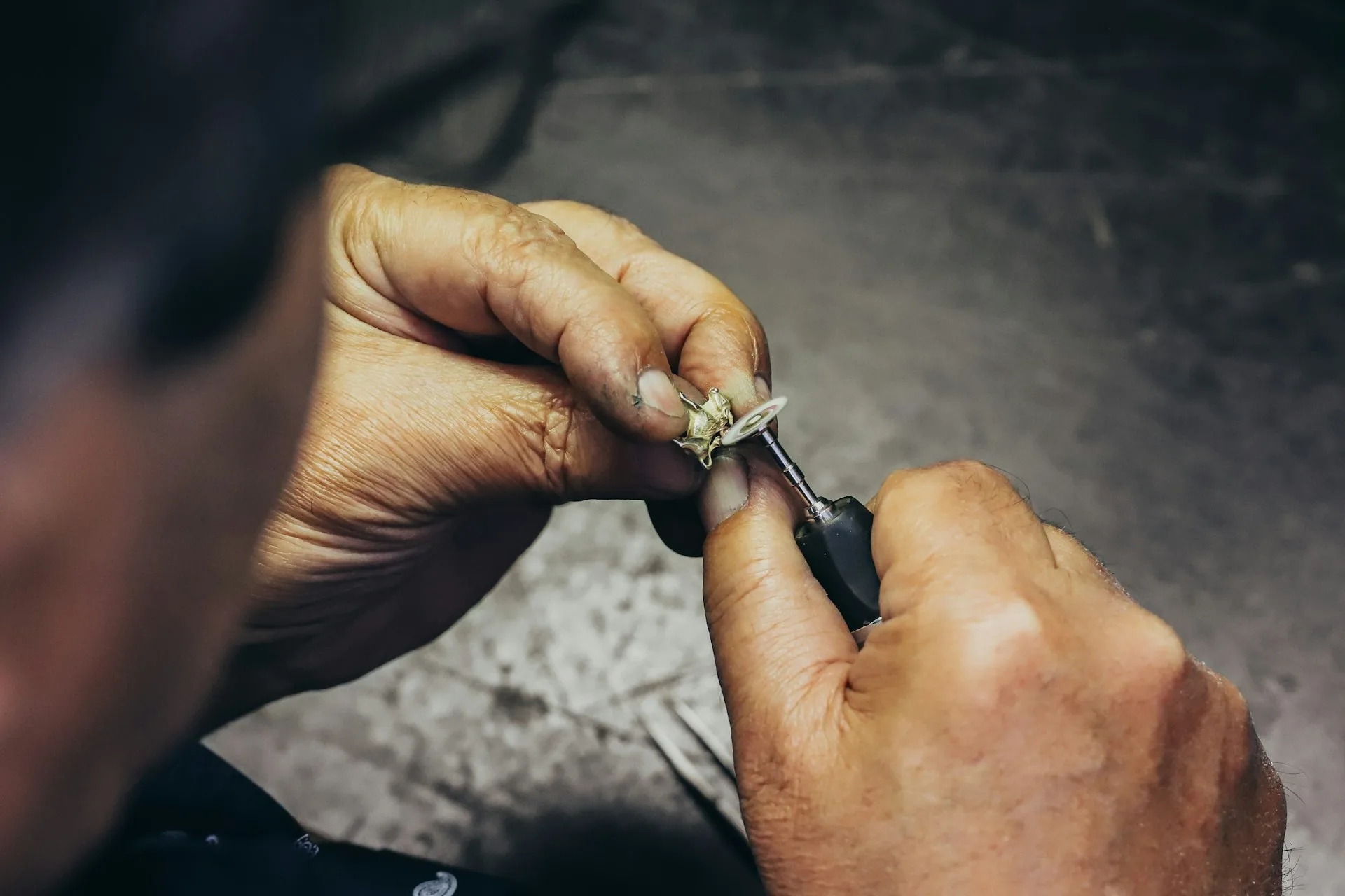 Mains d'artisan tenant un outil de précision sur un établi d'atelier