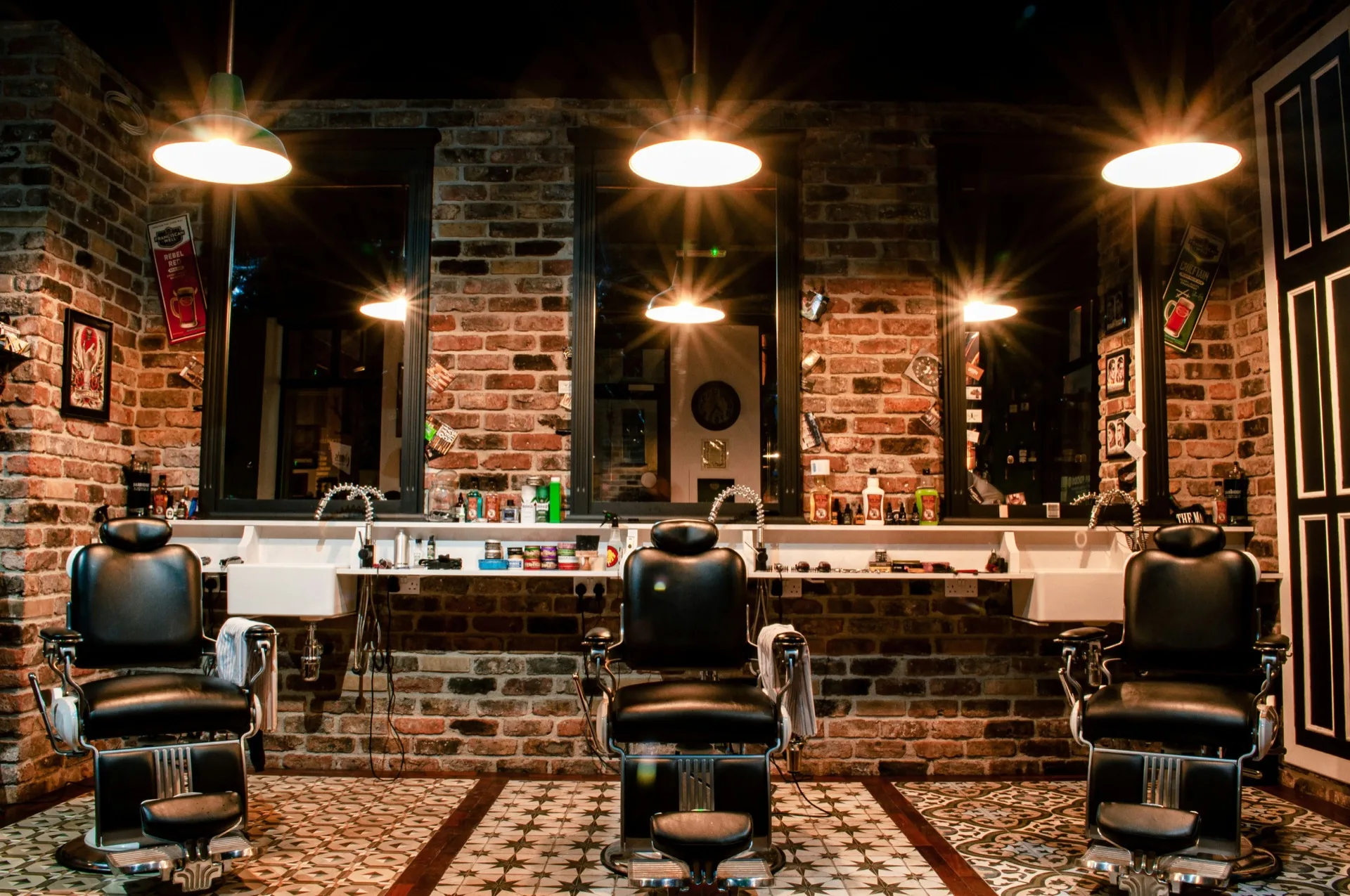 Fauteuil de barbier en cuir noir devant un mur de briques apparentes