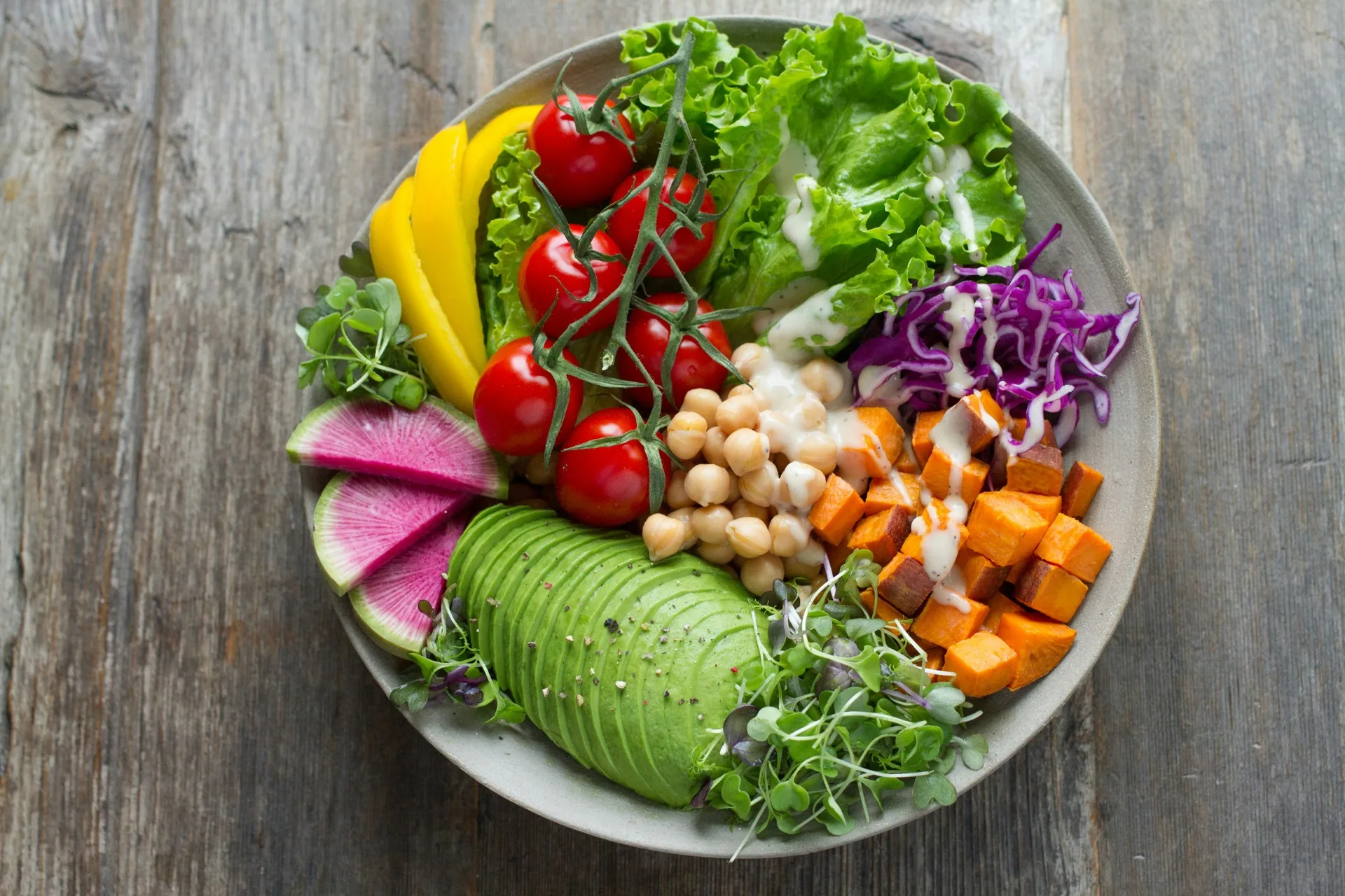 Bol coloré de légumes frais, avocat, tomates cerises, pois chiches et patate douce vu de dessus