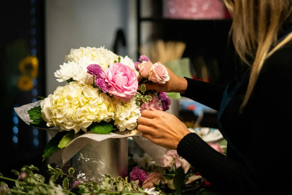 Mains composant un bouquet de roses et hortensias dans un atelier de fleuriste
