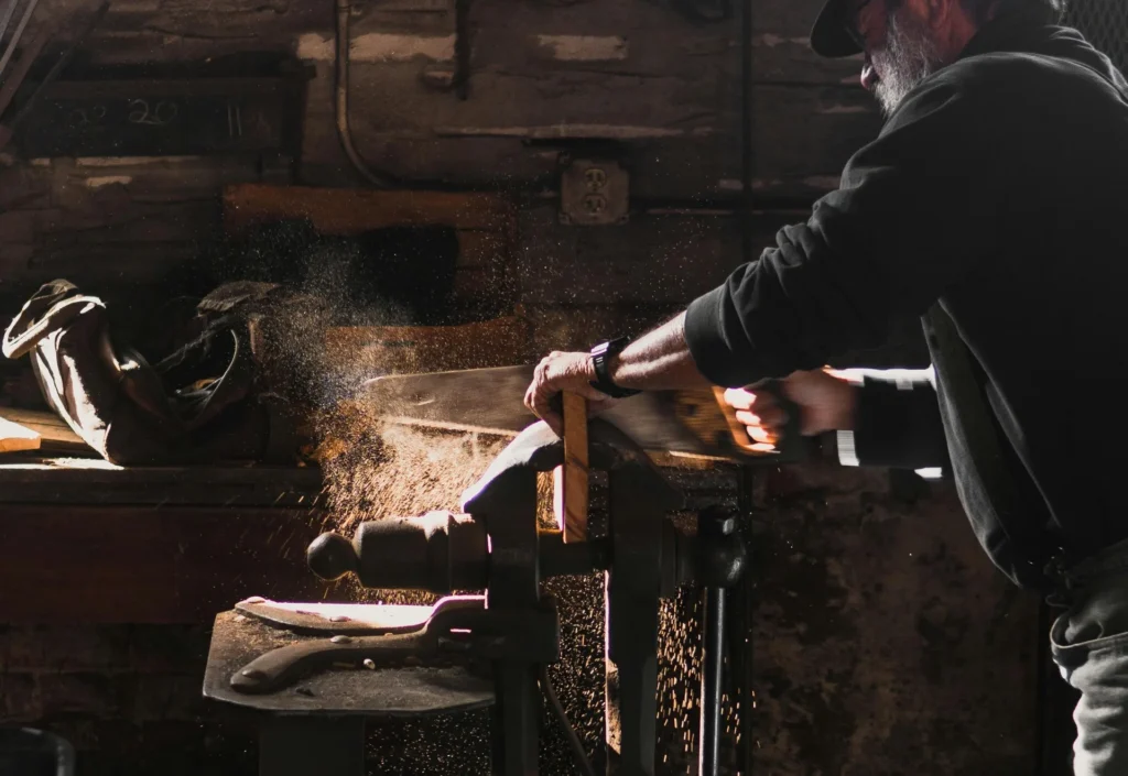 Artisan sciant une pièce de bois sur un établi avec copeaux en suspension
