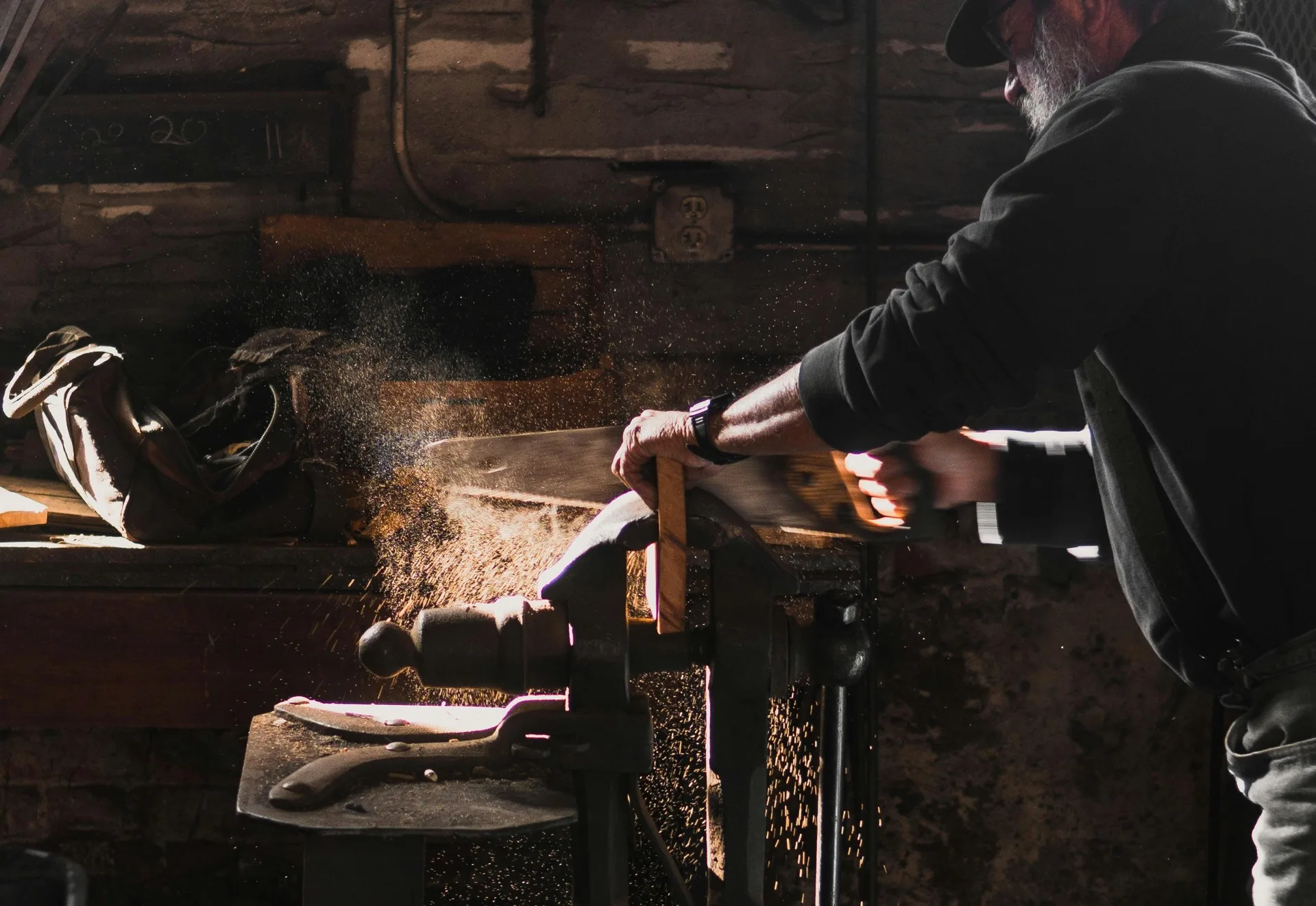 Artisan sciant une pièce de bois sur un établi avec copeaux en suspension