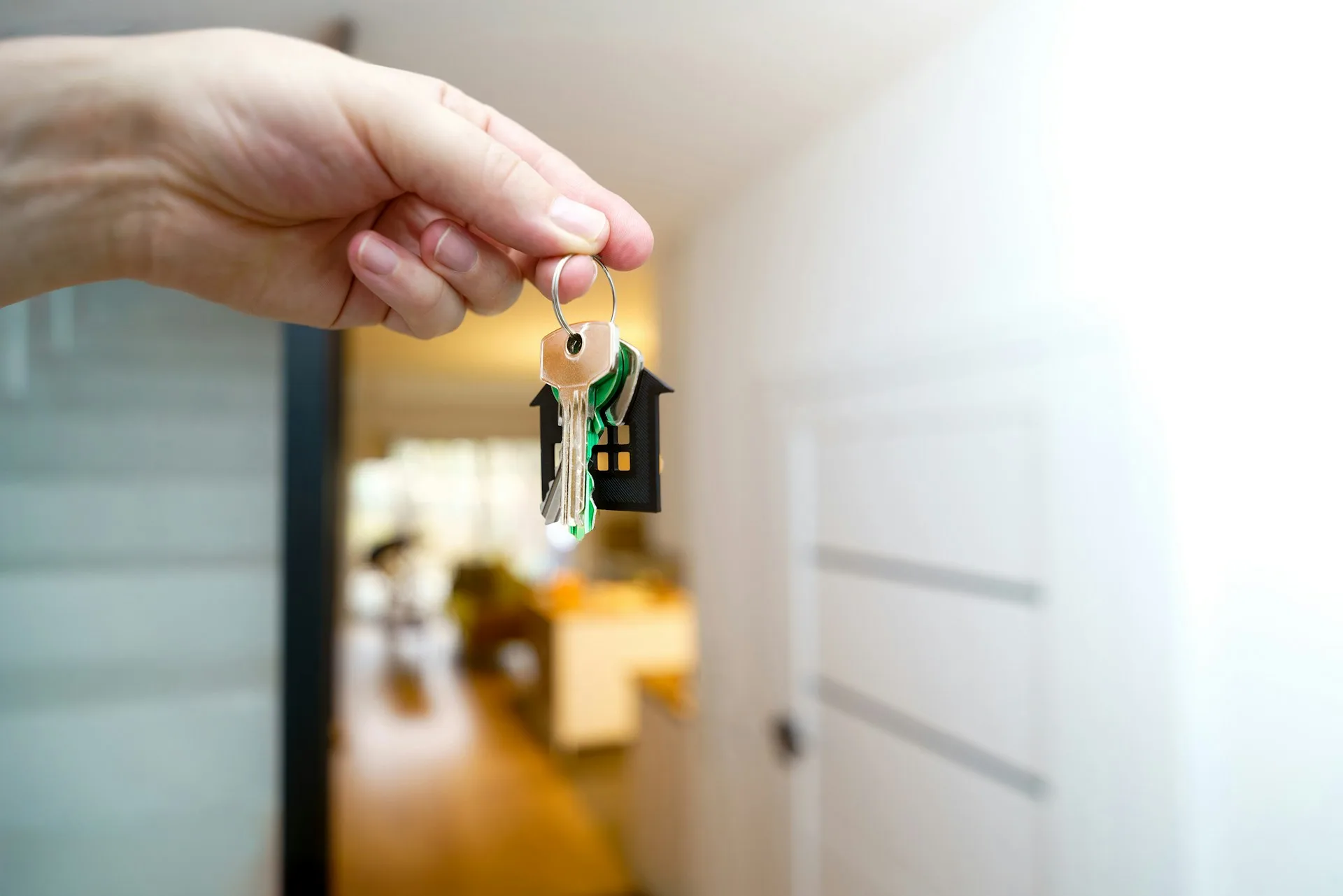 Mains tenant les clés d'une maison devant la porte d'entrée d'un nouveau logement.