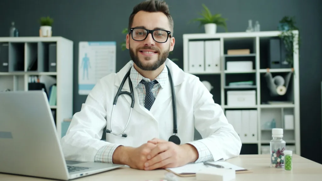 Médecin en blouse blanche assis à son bureau avec un stéthoscope dans un cabinet de consultation.