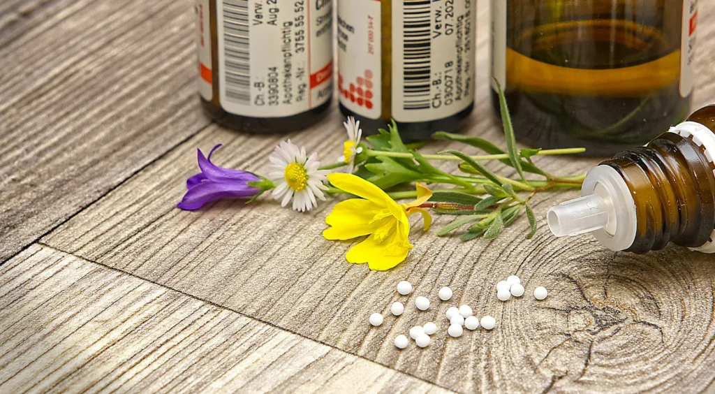 Flacons d'élixirs et de teintures à base de plantes médicinales sur une table en bois clair, ambiance naturopathie.