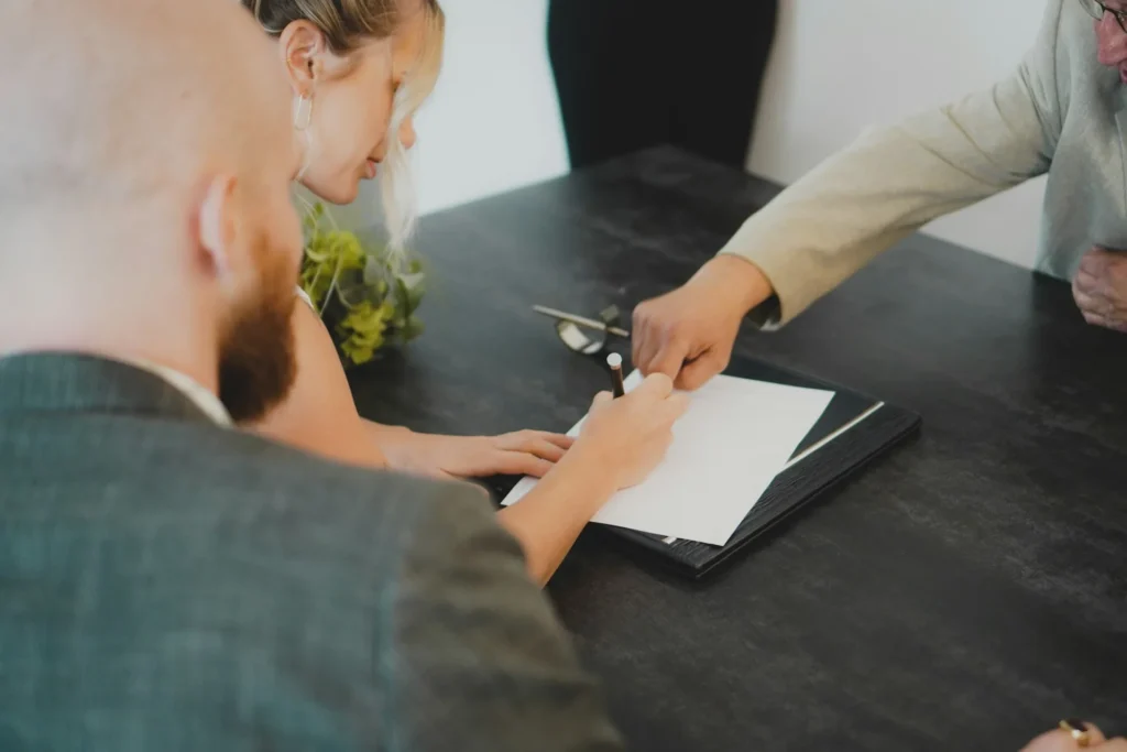 Couple en train de signer un acte à un bureau, scène typique d'une signature notariale.